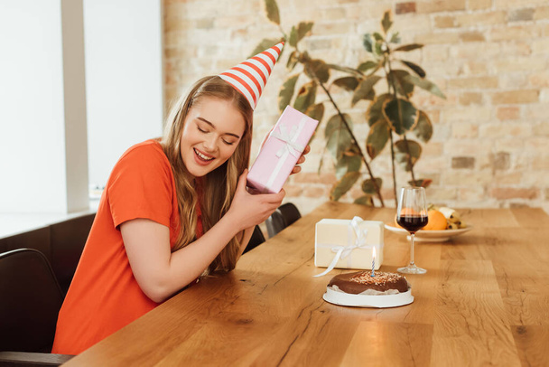 iloinen tyttö tilalla läsnä lähellä lasi punaviiniä ja syntymäpäivä kakku
  - Valokuva, kuva