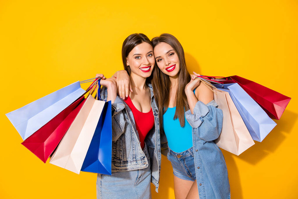 Portrait of nice attractive pretty charming perfect glamorous cheerful girls carrying colorful bags spending free time isolated on bright vivid shine vibrant yellow color background - Zdjęcie, obraz