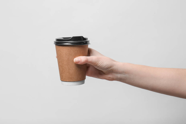 Hand with takeaway cup for drink on light background - Foto, immagini