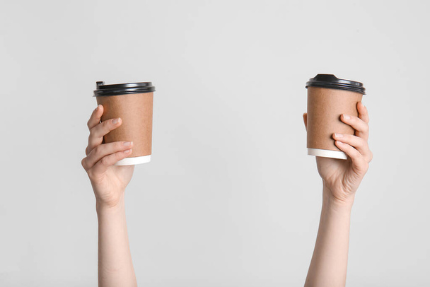 Hands with takeaway cups for drink on light background - 写真・画像