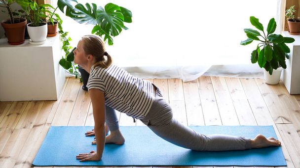 Quédate en casa. mujer enmascarada haciendo yoga en el salón durante la cuarentena
 - Foto, Imagen