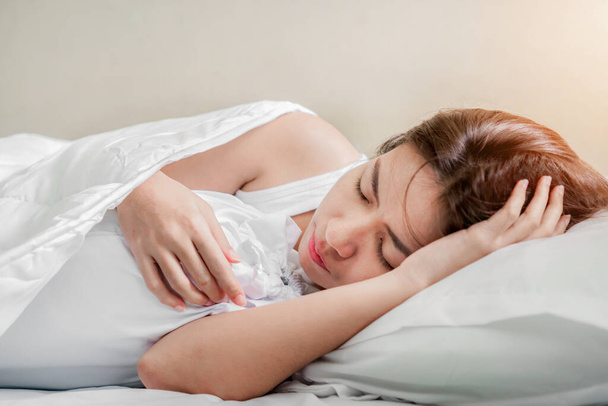 Young asian woman sleeping alone on white pillow on bed in bedroom on morning time, copy space. - Photo, Image