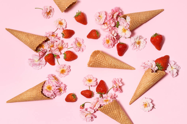 Ice cream cones with strawberries and small roses on a pink background - Fotoğraf, Görsel