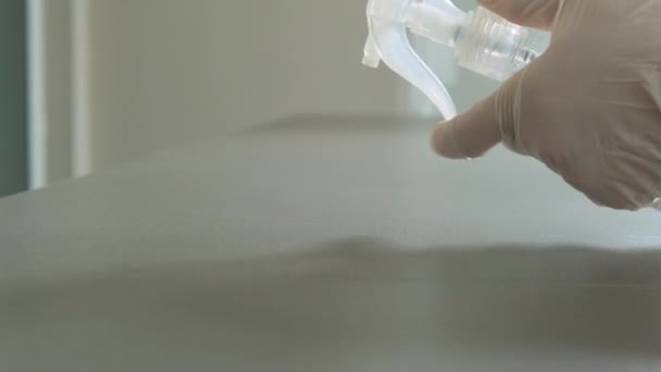 Hände in medizinischen Handschuhen sprühen Desinfektionsmittel und wischen die Oberfläche mit einem Lappen ab - Filmmaterial, Video