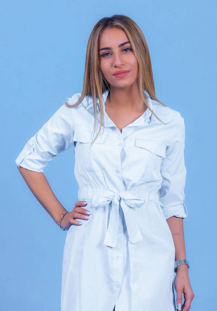 portrait Attractive young blonde model posing in trendy dress isolated at blue studio background. Beautiful girl standing in trendy clothing looking at camera, - Φωτογραφία, εικόνα