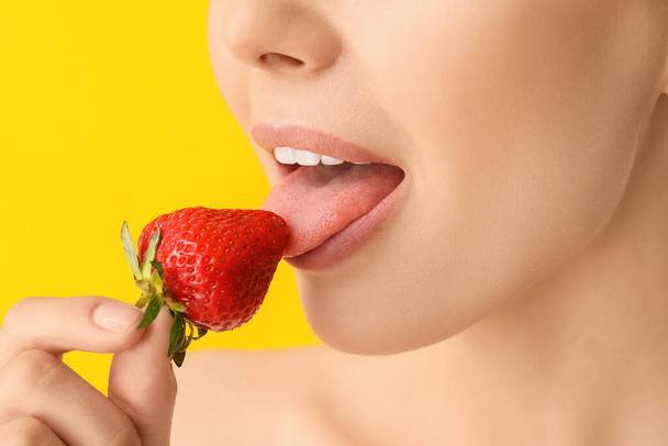 Sexy young woman with strawberry on color background, closeup - 写真・画像