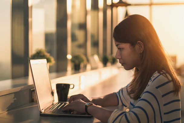 Jovem mulher asiática trabalhando em um laptop e sentar em casa escritório no horário da manhã
. - Foto, Imagem