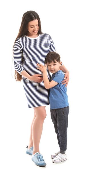 Krásná těhotná žena se svým malým synem na bílém pozadí - Fotografie, Obrázek