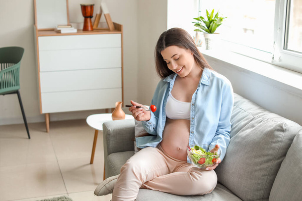 Hermosa mujer embarazada comiendo ensalada en casa
 - Foto, Imagen