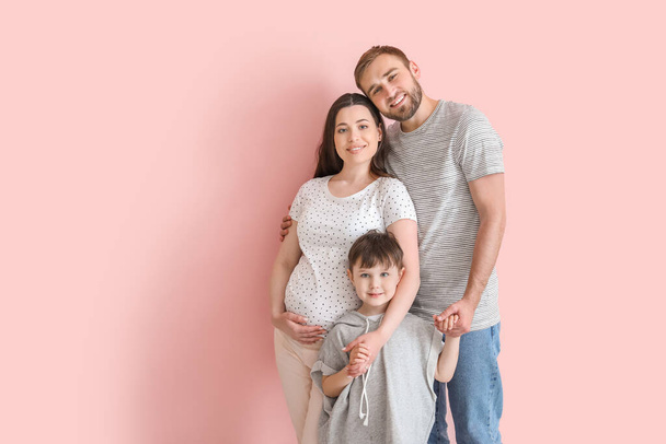 Красивая беременная женщина со своей семьей на цветном фоне - Фото, изображение
