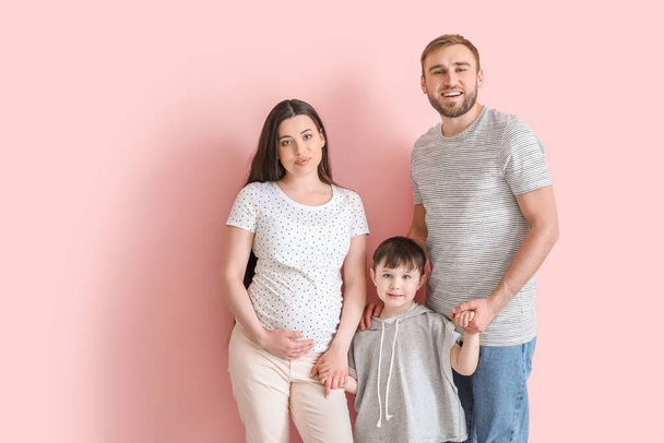 Schöne schwangere Frau mit ihrer Familie auf farbigem Hintergrund - Foto, Bild