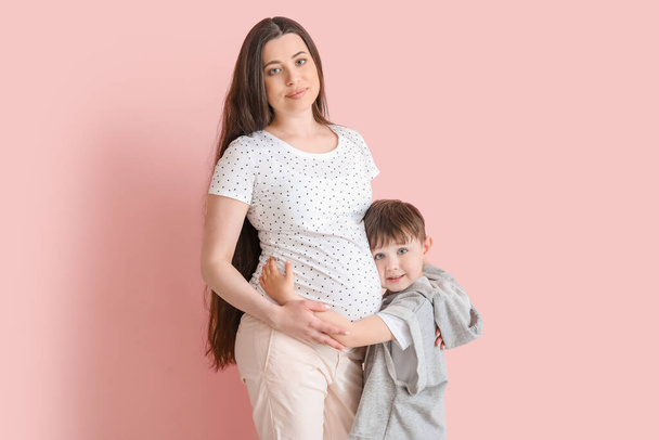 Красивая беременная женщина со своим маленьким сыном на цветном фоне
 - Фото, изображение