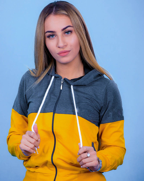 portrait Attractive young blonde pretty young model girl in sportswear posing in blue backround, - Photo, Image