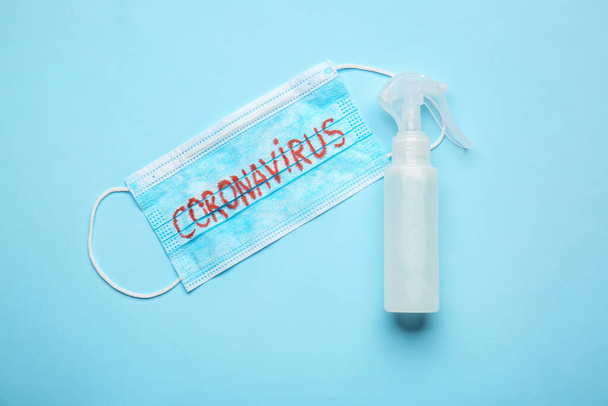 Απολυμαντικό και ιατρική μάσκα με κείμενο CORONAVIRUS σε έγχρωμο φόντο - Φωτογραφία, εικόνα