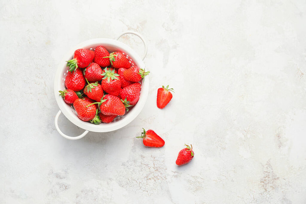 Colander with ripe strawberry on light background - Фото, изображение