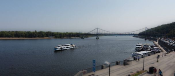 Ένα σκάφος αναψυχής που επιπλέει στο ποτάμι. Εφέ μετατόπισης. Μικροσκοπικό φαινόμενο. Ποταμός Δνείπερου στο Κίεβο. - Φωτογραφία, εικόνα