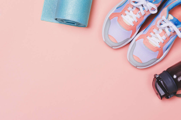 Yoga mat, sport shoes, bottle of water on pink background. Healthy lifestyle. Copy space - Fotó, kép
