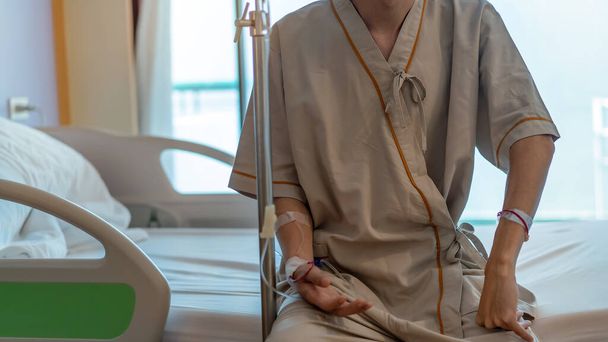 Asian man patient with medical drip or IV drip sitting on bed in hospital ward, Selective focus, Healthcare concept. - Foto, Imagen