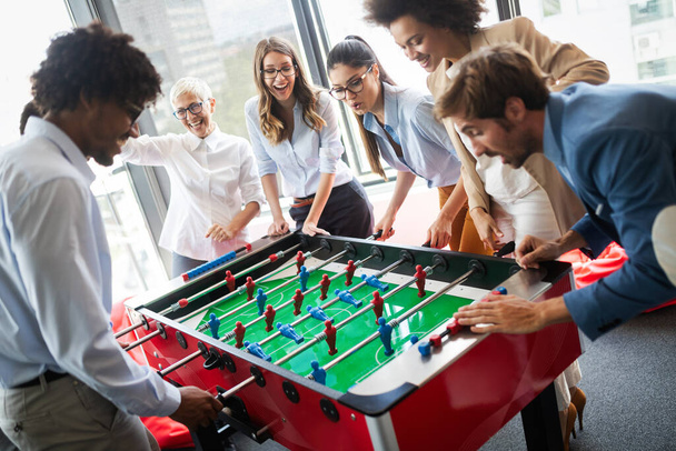 Employees playing table soccer indoor game in the office during break time to relieve stress from work - Foto, imagen