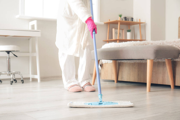 Hausfrau im Schutzanzug putzt Fußboden im Schlafzimmer - Foto, Bild
