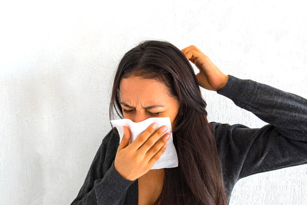 Mulher hispânica doente e espirra com papel de seda na mão, Conceito de Atenção à Saúde
. - Foto, Imagem