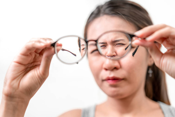 Азійська жінка тримає окуляри на білому тлі, вибіркове фокусування на окулярах, міопаї та проблемах зору.. - Фото, зображення
