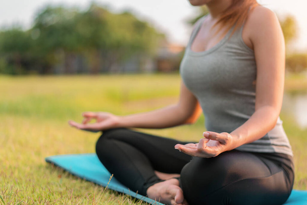 Asian woman meditating and sit in the lotus pose at park, Healthy and Yoga Concept,Mind-body improvements concept, Selective focus, Copy space. - Valokuva, kuva