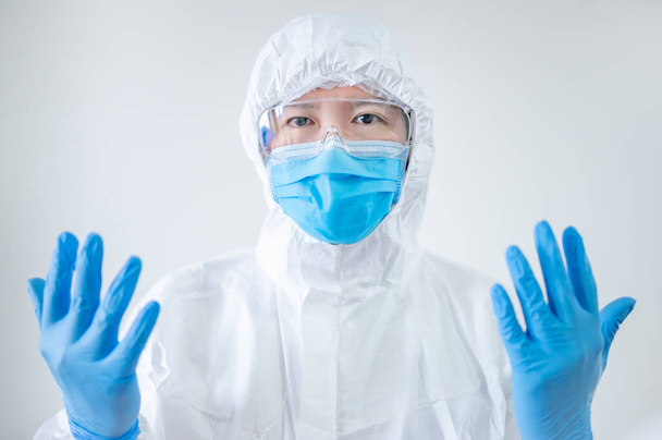 Γιατρός ή ιατρός σε μέσα ατομικής προστασίας με αποστειρωμένα λαστιχένια γάντια σε νοσοκομειακή κλινική. Ιατρός που φοράει κοστούμι, μάσκα και γυαλιά PPE για την πρόληψη της λοίμωξης από τον ιό Coronavirus (COVID-19) - Φωτογραφία, εικόνα