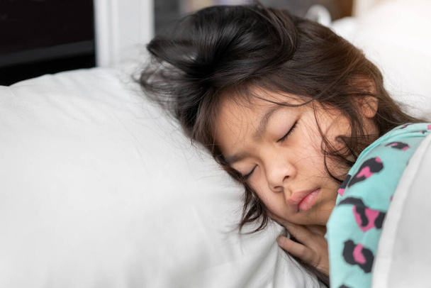 Young asian girl sleeping on white pillow on bed in bedroom in morning time, Selective focus, Copy space. - Foto, immagini