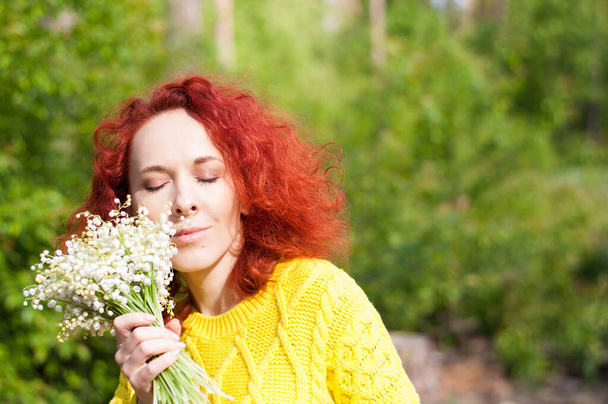 close up vermelho cabelo sonhador menina com olhos fechados posando com buquê de flores brancas em suéter amarelo
 - Foto, Imagem