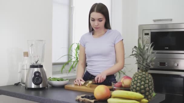 Mujer cortar un plátano pelado para hacer el batido
 - Imágenes, Vídeo