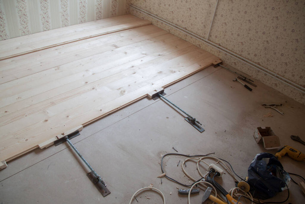 installatie van houten vloer. reparatie van een houten vloer. Trekkers voor planken. klemmen voor planken - Foto, afbeelding