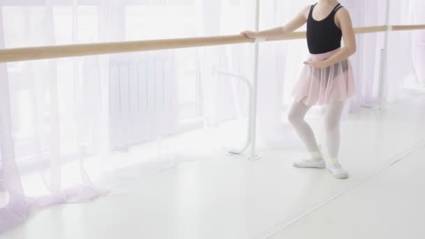 Молодая балерина делает упражнения возле балетной площадки в студии
. - Кадры, видео