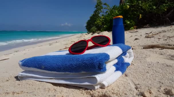 Zonnebril met handdoek en lotion fles op het strand. Tropische vakantie op Bali, Indonesië.     - Video