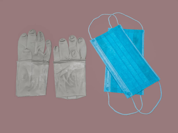 Een paar rubber medische handschoenen en chirurgische masker geïsoleerd op grijze achtergrond - Foto, afbeelding