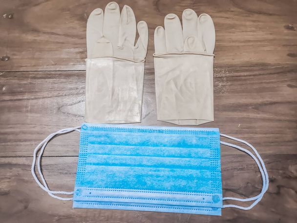 Un par de guantes médicos de goma y máscara quirúrgica en una mesa de madera
. - Foto, imagen