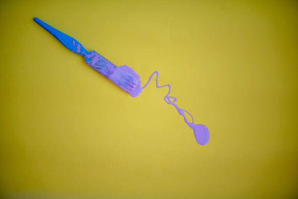 Пензлик з фіолетовою фарбою ізольовано на жовтому тлі
 - Фото, зображення