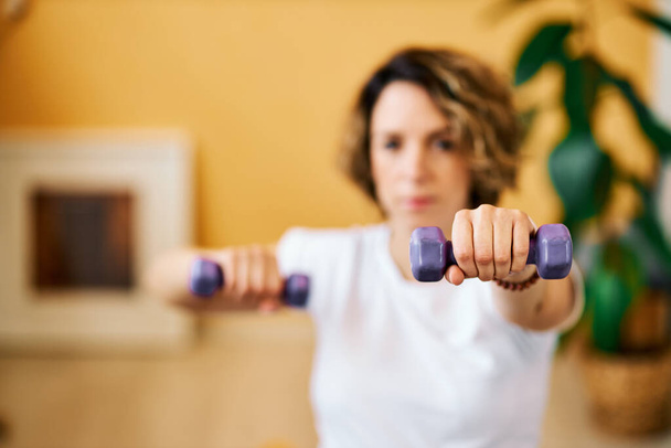 Closeup of middle aged pregnant woman doing fitness exercises with dumbbells. - Photo, Image