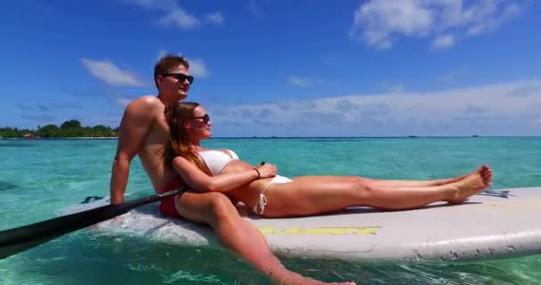 Beach fun couple on paddleboard surfboard surfing together in ocean sea on Big Island, Hawaii - Footage, Video