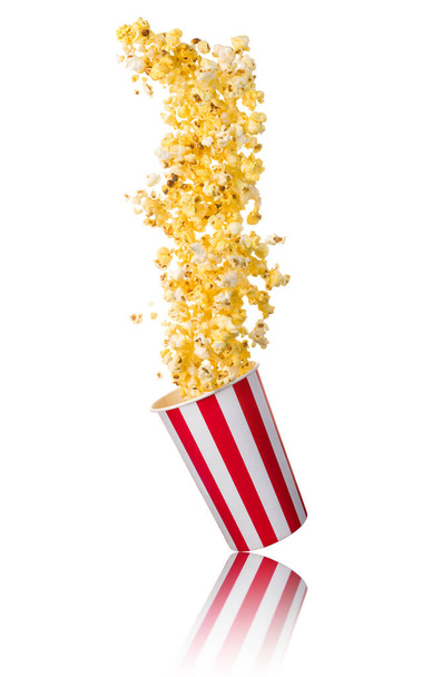 Flying popcorn from paper striped bucket isolated on white background with clipping path. Concept of cinema or watching TV. - Foto, afbeelding