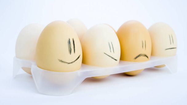 Eggs in a tray with funny emotions.White background. - Фото, зображення