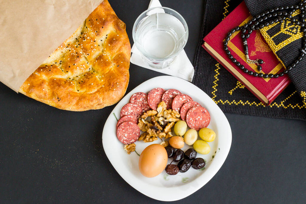Dilimlenmiş Ramazan ekmeği, zeytin bir bardak su, beyaz üzerine kutsal kitap. Ramazan konsepti.. - Fotoğraf, Görsel