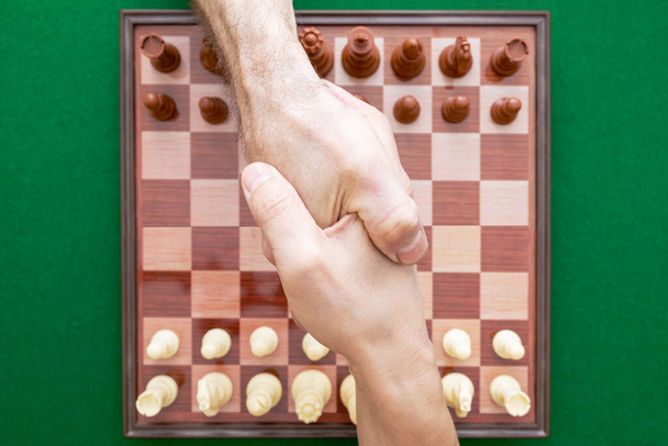 Image de serrer la main d'un homme sur les échecs. Journée mondiale des échecs. Journée internationale des échecs. Le 20 juillet. Vue d'en haut
. - Photo, image