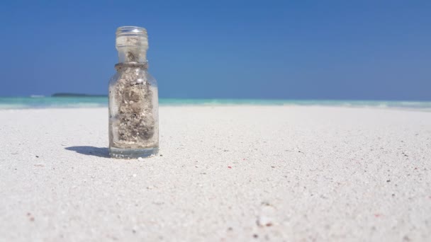 Pequeña botella de vidrio en la playa de arena. Escondido de Australia, Oceanía.  - Imágenes, Vídeo