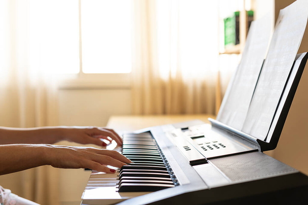 Cerrar la mano de la mujer tocando el piano mientras aprende de casa durante la cuarentena. Estudiante de piano. Pianista
. - Foto, imagen