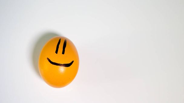 Yellow chicken egg with a smiley on a white background. - Фото, зображення