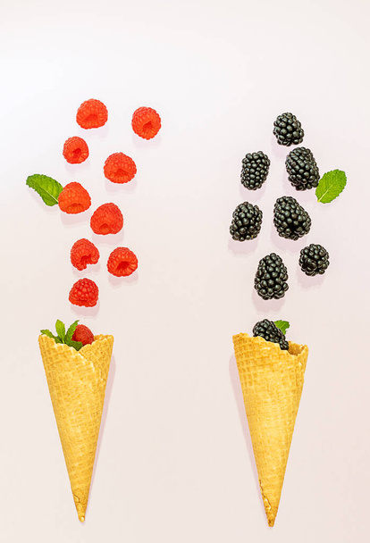 Framboise et mûre sont tombées dans deux cônes de crème glacée. Concept d'été
. - Photo, image