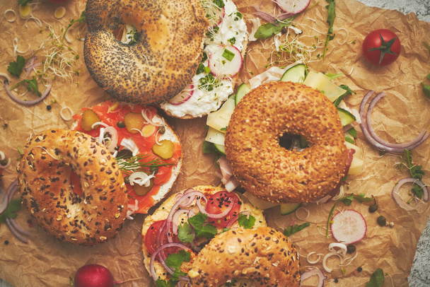 Tasty colorful various bagels with healthy ingredients served on brown baking paper - Photo, Image