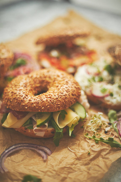 Sandwiches de bagel con diversos ingredientes, salmón, requesón, hummus, jamón, rábano y hierbas frescas - Foto, Imagen
