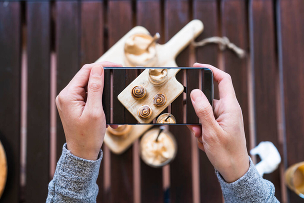 Mujer tomando fotos con su smartphone de un delicioso café Delicioso Daytona
  - Foto, Imagen